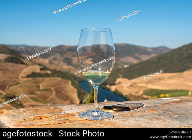 Glass of white wine for tasting above the hillsides of the Douro valley in Portugal