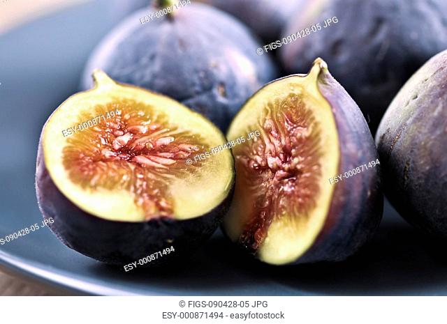 Closeup view of figs sliced in half on a blue plate