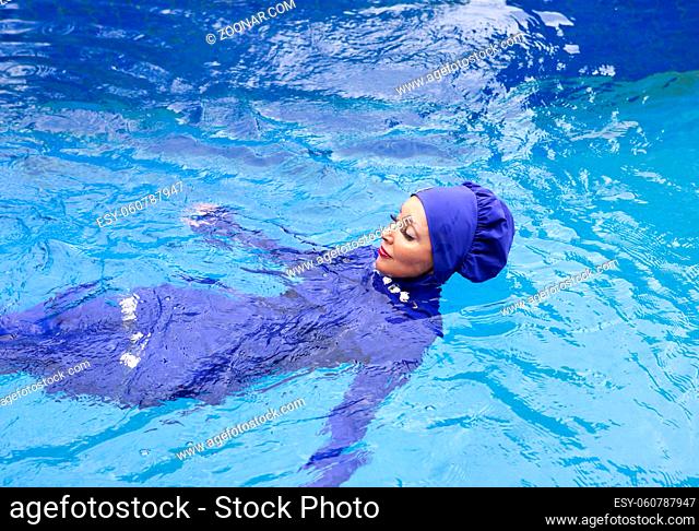 attractive woman in a Muslim swimwear burkini swims in the pool