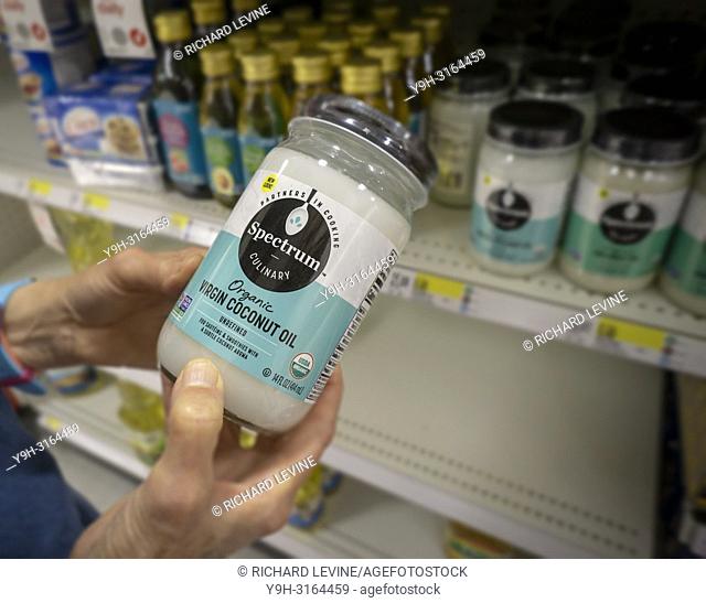 A consumer chooses a jar of Spectrum brand virgin organic coconut oil in a grocery in New York on Monday, August 27, 2018