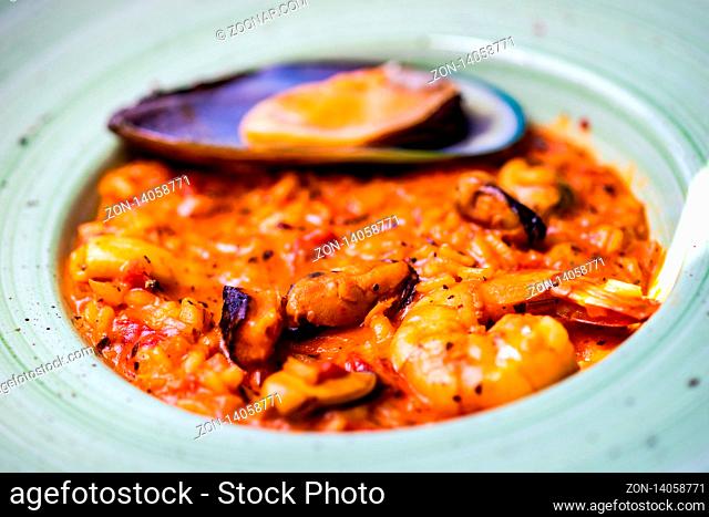 Italian risotto with seafood, served with glass of dry white wine, lemons and salt on concrete background with copy space