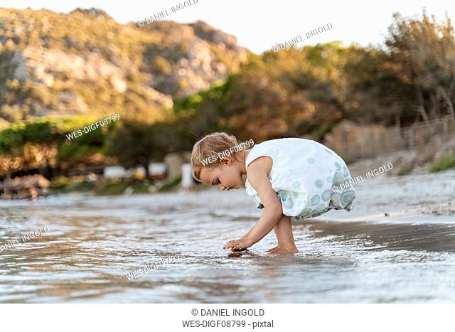 Cute toddler girl playing on the beach