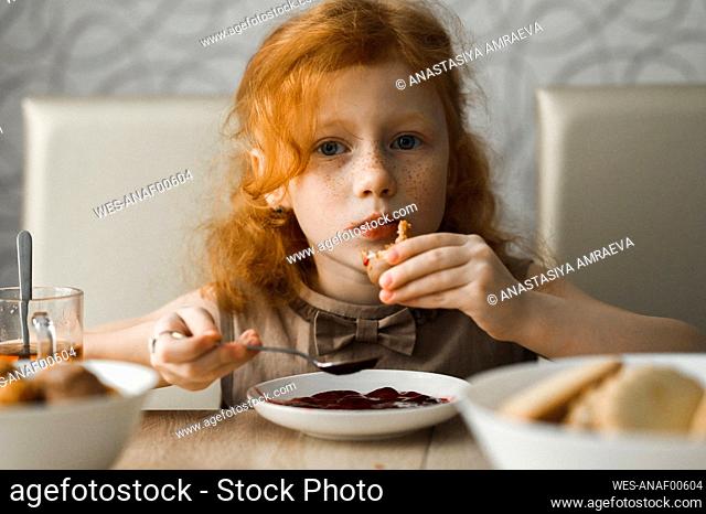 Redhead girl having breakfast at home