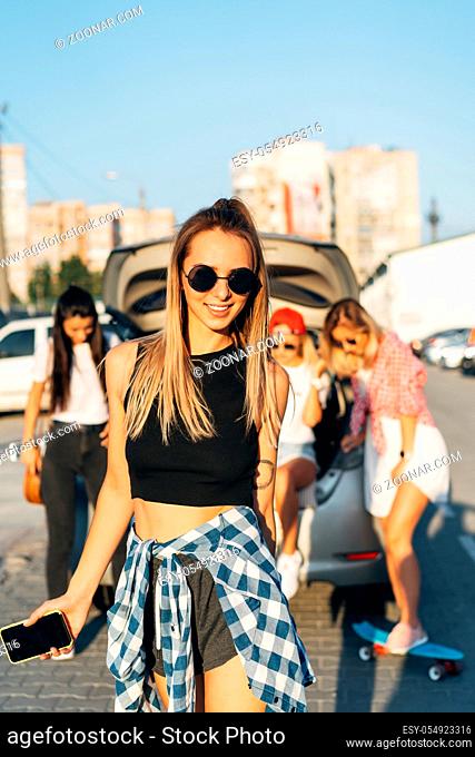 Beautiful young girl in sunglasses posing for the camera at the car park