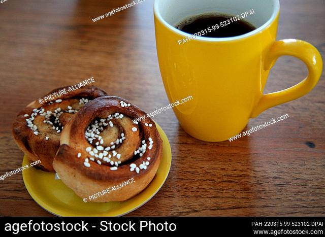 ILLUSTRATION - 14 March 2022, Denmark, Kopenhagen: Two cinnamon buns lie next to a coffee mug. A secret ingredient of Swedish happiness is found in the daily...