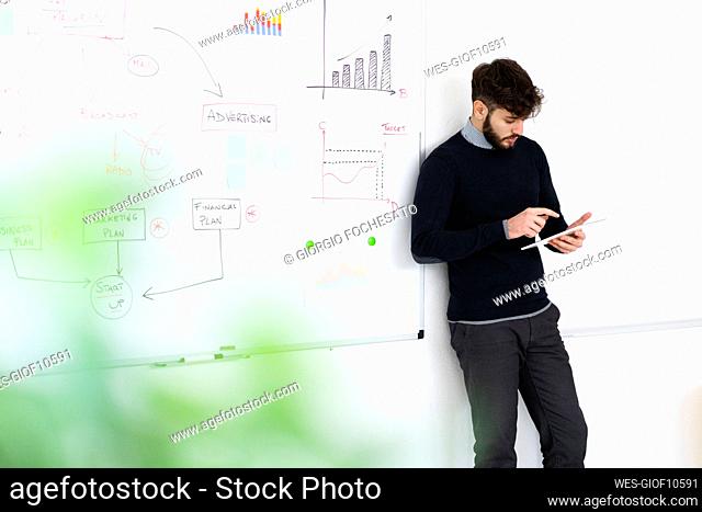 Businessman using digital tablet in front of whiteboard in office