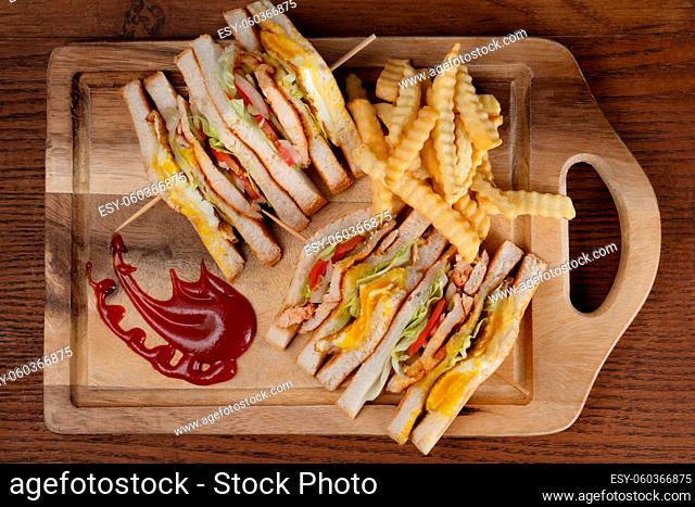 Top view of chicken club sandwiches and french fries isolated on wooden table