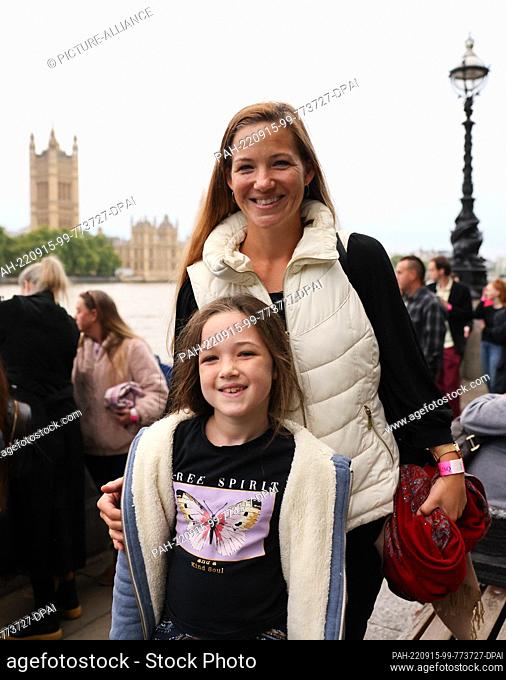15 September 2022, Great Britain, London: Colleen Connors and her daughter Lily (7 years old) from London stand next to a long queue on the Thames near...