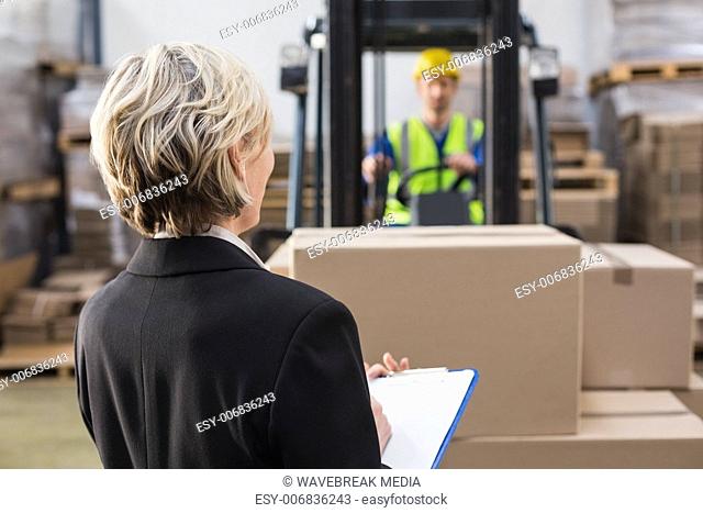 Rear view of warehouse manager in front of her colleague
