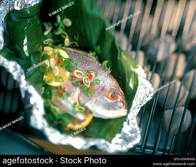 Whole Fish in a Banana Leaf with Scallions and Lemon on a Charcoal Barbecue