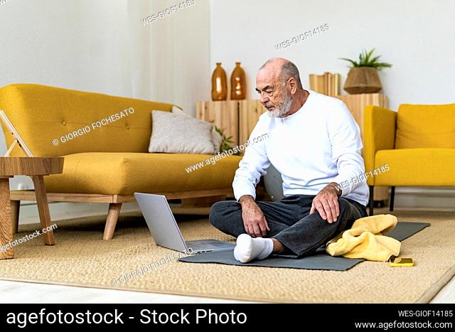 Senior man watching tutorial on laptop at home