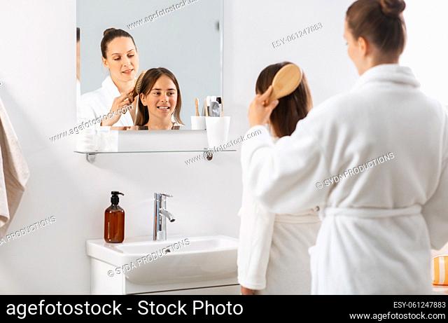 mother and daughter brushing hair at bathroom