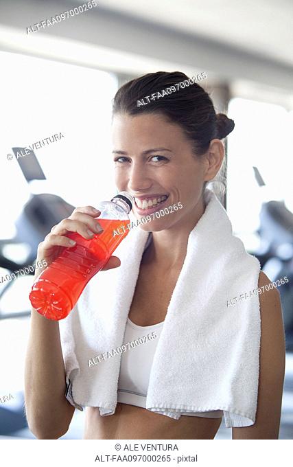 Woman hydrating with sports drink in health club
