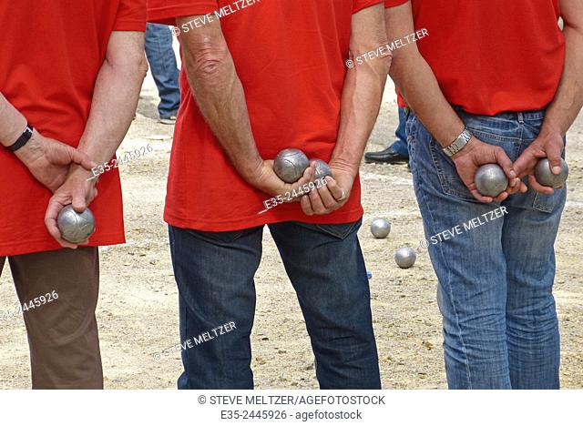 A team of petanque players watch their competition take its turn