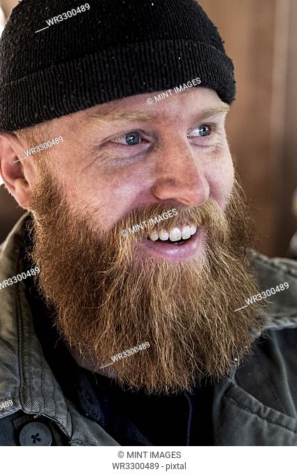 Portrait of smiling bearded man with light brown hair, wearing black beanie
