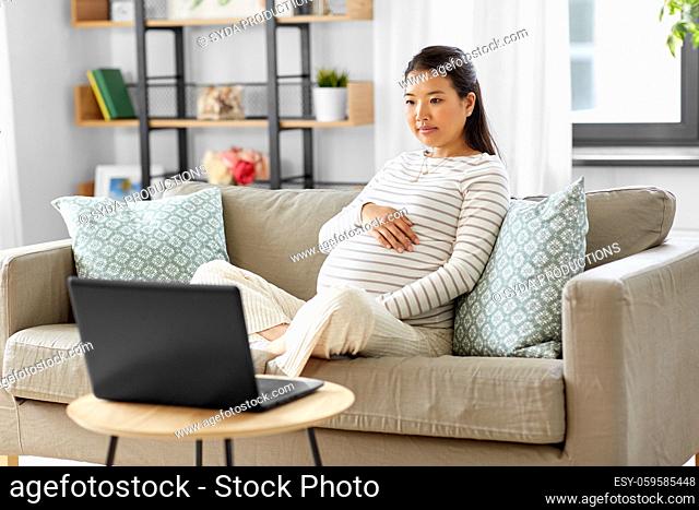 pregnant asian woman with laptop at home