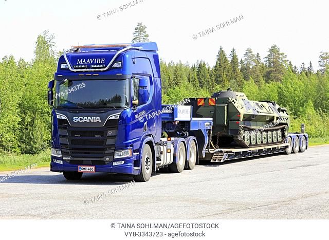 Orivesi, Finland. June 6, 2019. New blue Scania R650 truck of Maavire with battle tank on flat bed trailer on truck stop yard on sunny day of summer