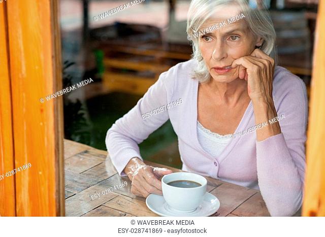 Thoughtful senior woman sitting by table