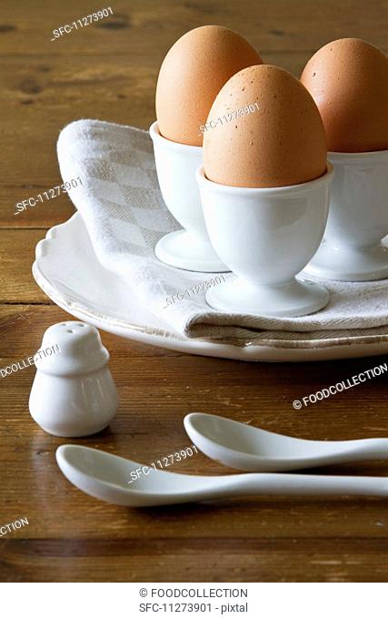 Three brown eggs in white porcelain egg cups