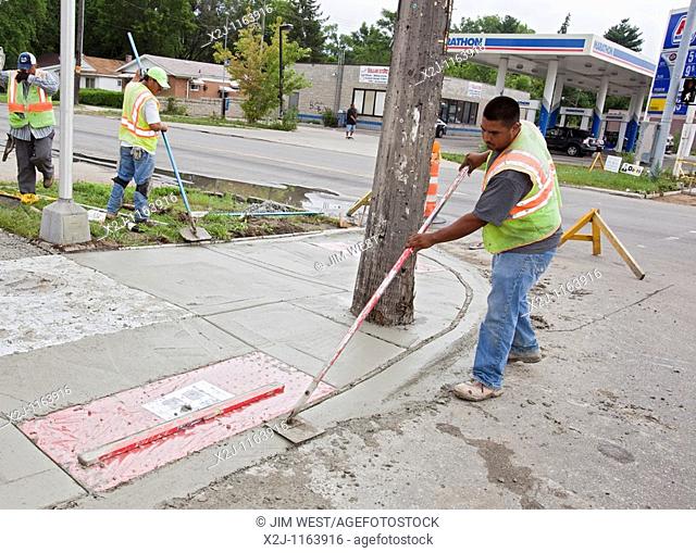 Detroit, Michigan - Workers install a curb ramp at a street intersection to allow access for people with disabilities  The ramps are required by the Americans...