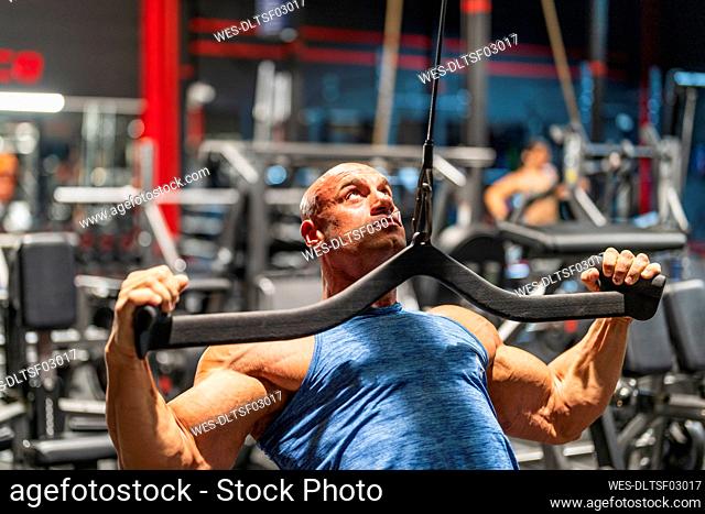 Determined bodybuilder pulling lat pulldown machine in gym