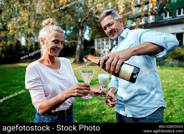 Man pouring champagne to woman at backyard