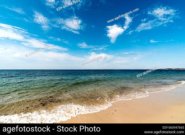 empty tropical beach with gentle waves and a great view over the calm ocean
