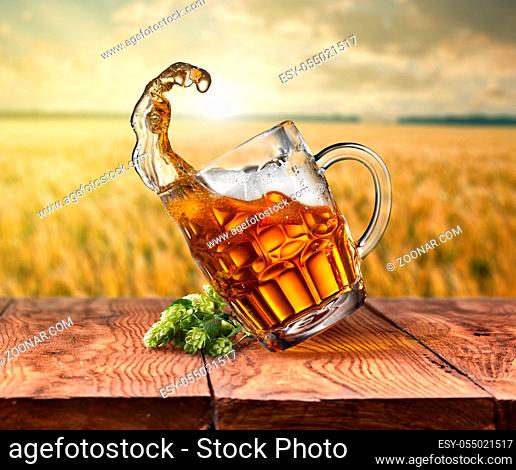 Glass of beer on empty wooden table with blurred sea on background, natural background with bokeh