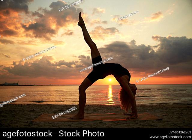 woman doing yoga bridge pose on beach