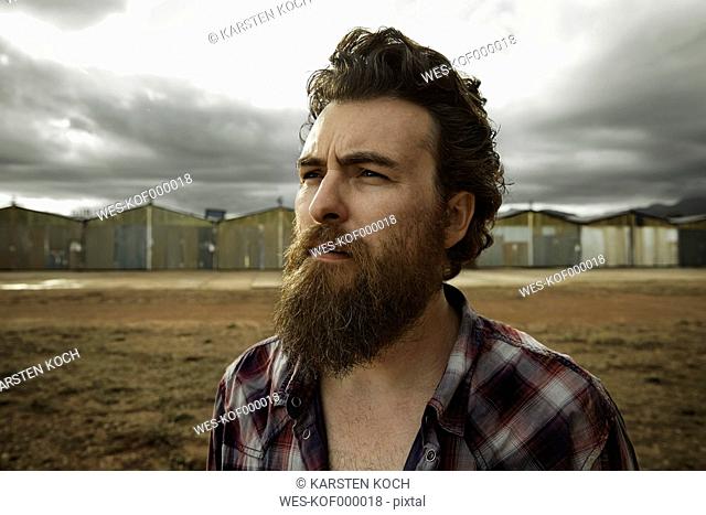 Serious man with full beard in abandoned landscape