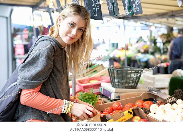 Young woman at greengrocer's shopping for fresh fruits and vegetables