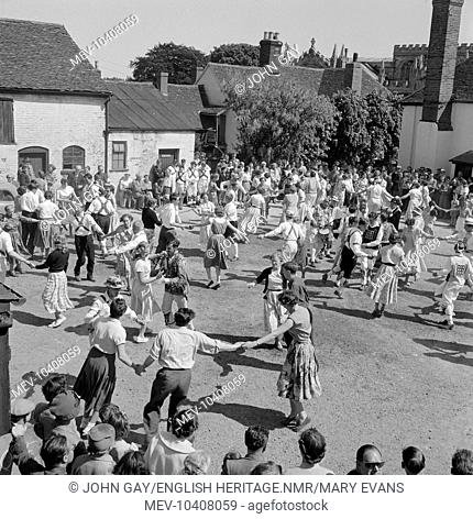 A crowd of people dancing with morris dancers in The Swan Hotel yard