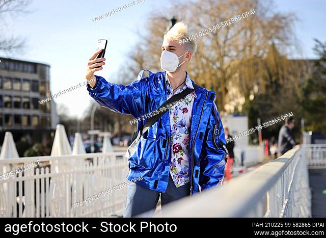 24 February 2021, Hamburg: Jendrik Sigwart, singer and musical performer, takes pictures with his smartphone during a photo session at the Alster