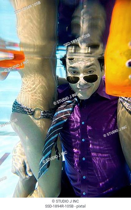 Businessman underwater with two women in a swimming pool