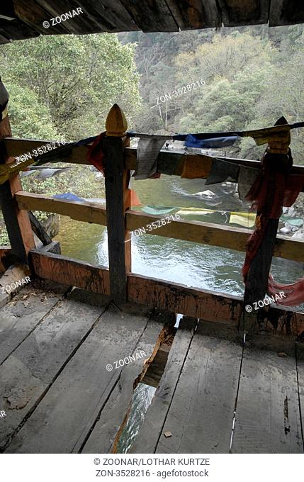 Rotten footbridge with prayer flags above the river Kulong Chu, Trashi Yangtse, East Bhutan