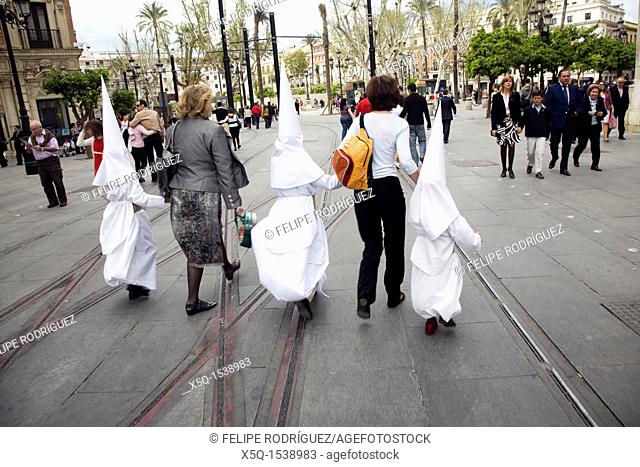Two women leading young penitents to the church for a Holy Week procession on Palm Sunday, Seville, Spain