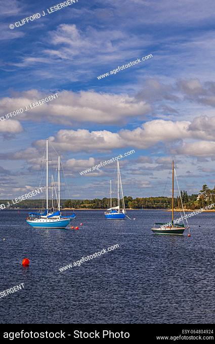 Three sailboats anchored in Mahone Bay, Nova Scotia on a sunny autumn day