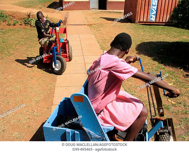 A young boy and girl use special carts to exercise their upper bodies during a physiotherapy session at the Kamapala School for the Physically Handicapped