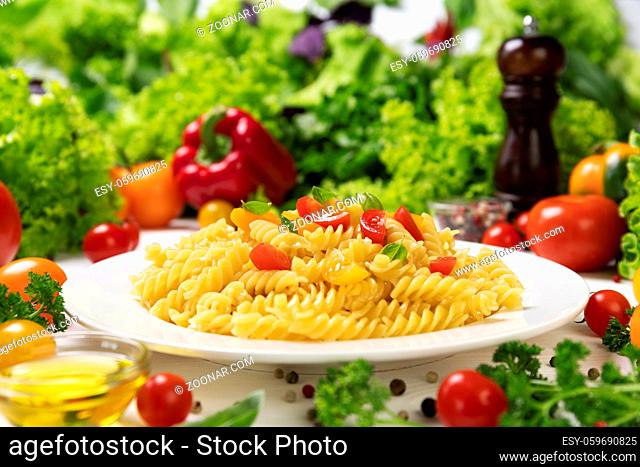 Plate of cooked italian fusilli pasta with tomatoes and basil leaves