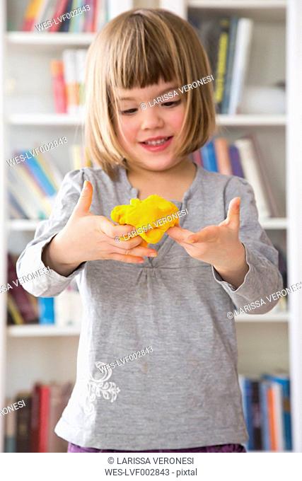 Little girl with yellow modeling clay