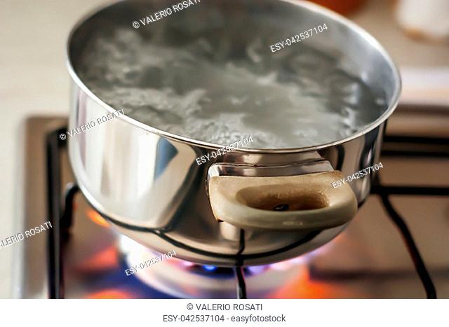 Water boiling in a pot over a lit stove. Cooking concept