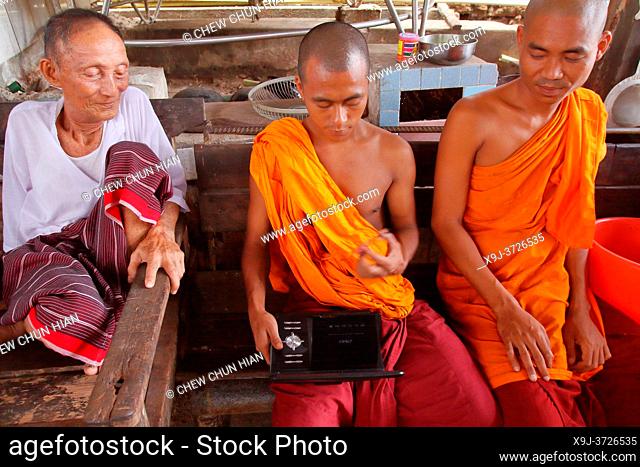 Monks sitting having a chat and watching movie, , Myanmar, Burma, Asia