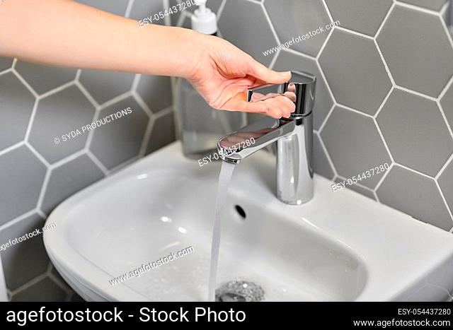 close up of woman's hand opening water tap