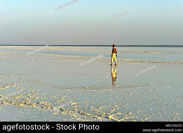 Tourist läuft über die Kruste aus Steinsalz auf dem Assale Salzsee, Hamadela, Danakil Depression, Afar Dreieck, Äthiopien / Tourist walkign across the salt...