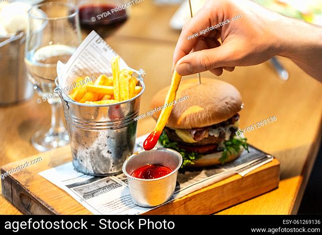 close up of hand dipping french fries to ketchup