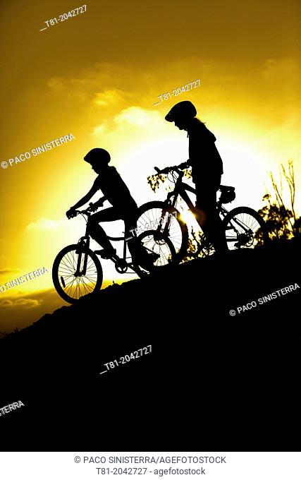 Girls silhouettes on bicycle at sunset in the Sierra de Cazorla, Andalucia, Spain