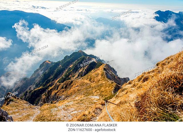 Via ferrata over the sea of clouds to bivouac Dino above Udine. The Alps, Italy