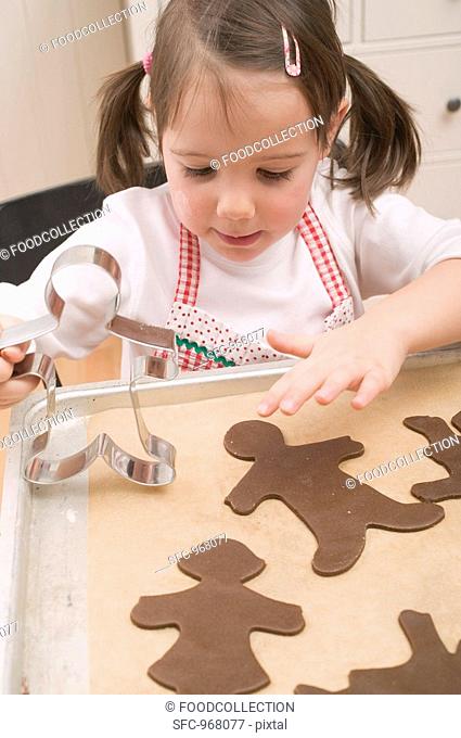 Small girl placing chocolate biscuits on baking tray