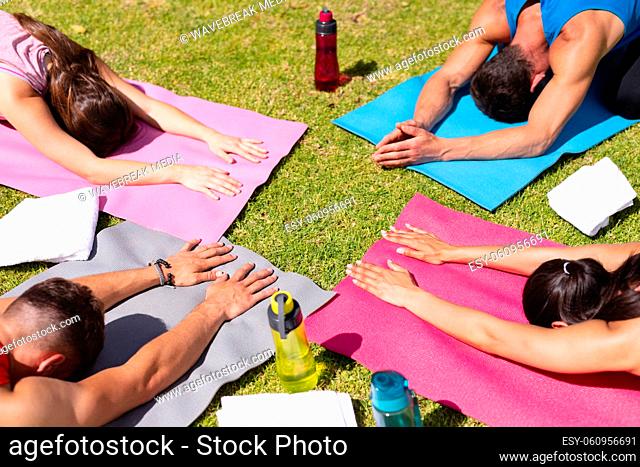 Men and women practicing yoga on exercise mats in park