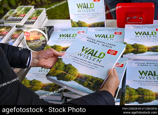 27 June 2023, Brandenburg, Potsdam: A woman holds the new book ""Waldwissen. Understanding the World from the Forest"" by Peter Wohlleben